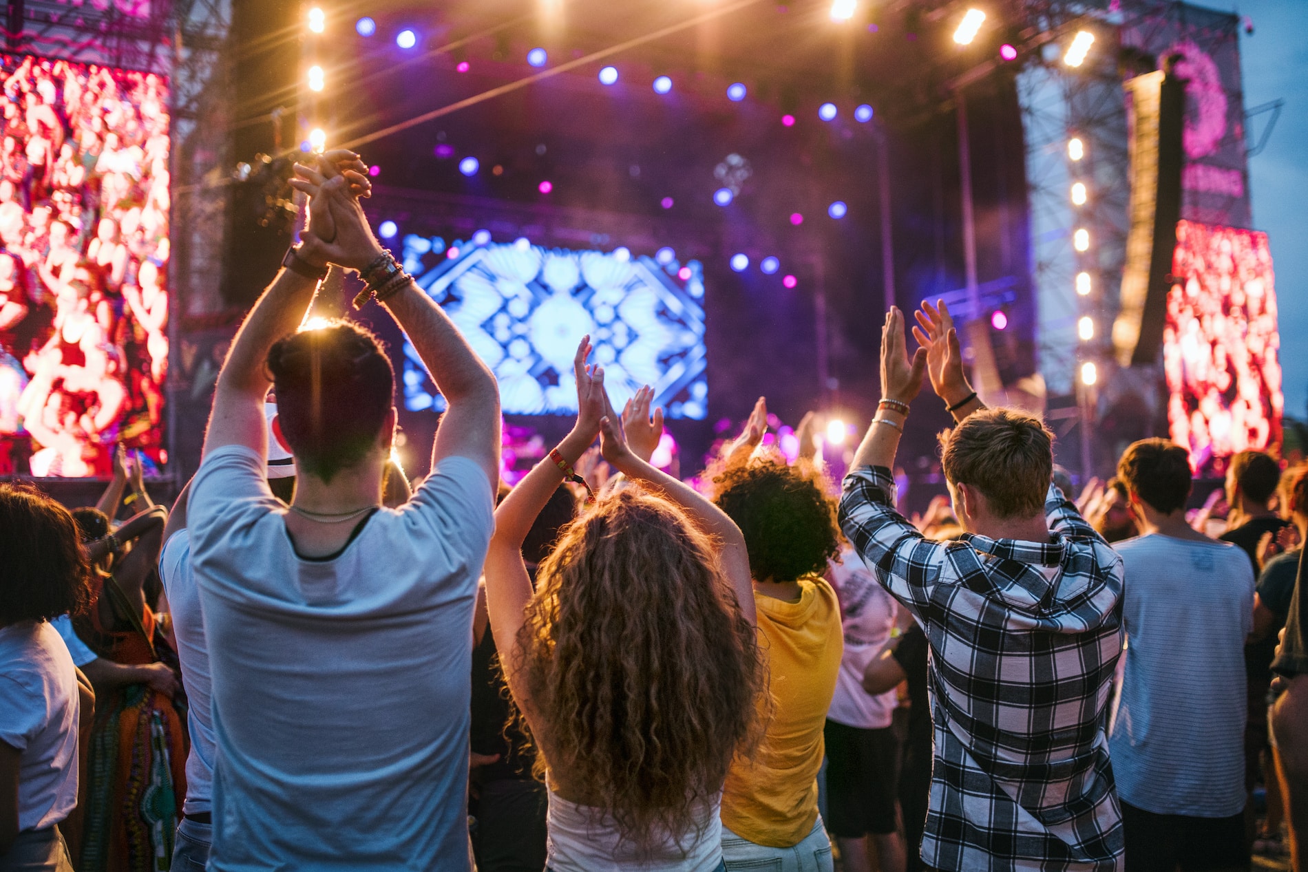 Rear view of group of young friends dancing at summer festival.