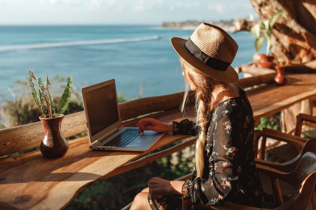 Business woman working with computer on the beach enjoying resort wifi